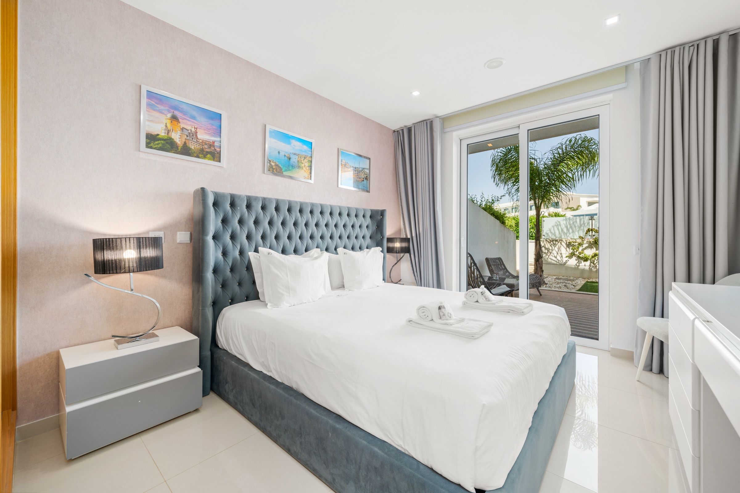 Quarto de casal com cabeceira capitoné azul-acinzentada e porta para o jardim